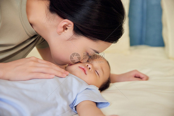 年轻妈妈亲吻睡觉的婴儿宝宝图片