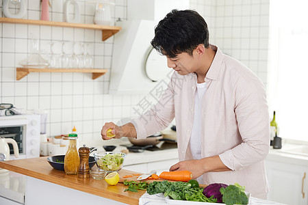 年轻男性做饭帅气的年轻男士在厨房做沙拉背景