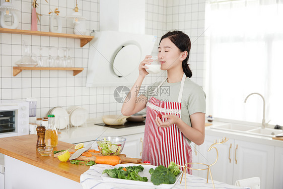 年轻女孩在厨房喝牛奶图片