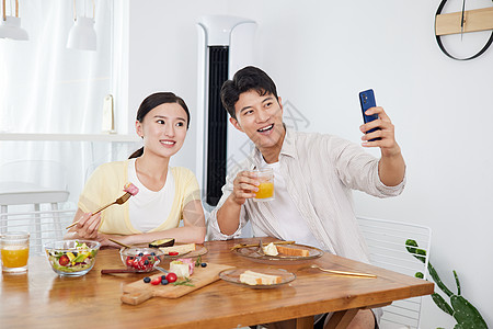 手机拍食物年轻情侣在餐厅用智能手机自拍背景