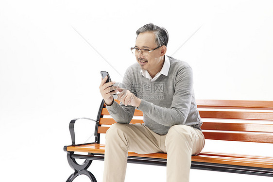 老年人坐在长椅上玩手机图片
