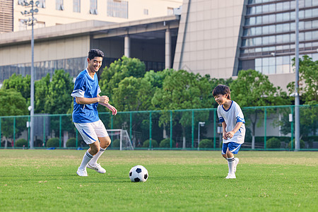 踢球动作父亲陪儿子在足球场踢足球背景