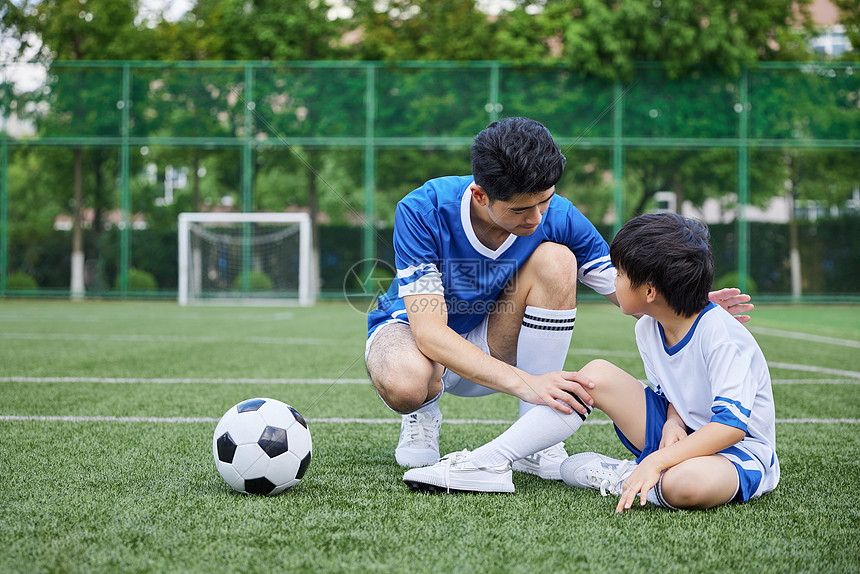 教练给男孩按摩受伤的膝盖图片