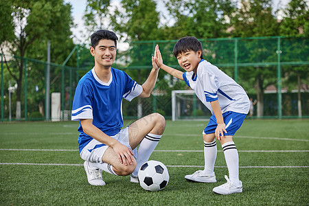 青少年足球训练足球教练和男孩在足球场踢球形象背景