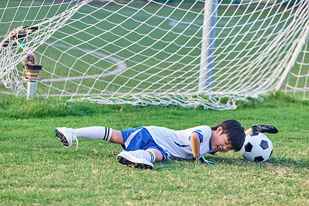 小男孩踢足球摔倒图片
