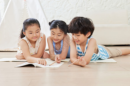三个小朋友趴在地板上写作业高清图片