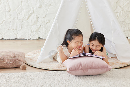 两个小女孩在帐篷里看儿童书高清图片