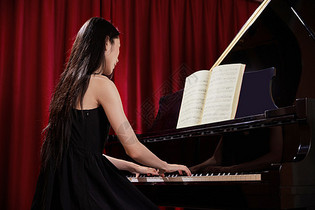 美女音乐教师弹奏钢琴背影图片