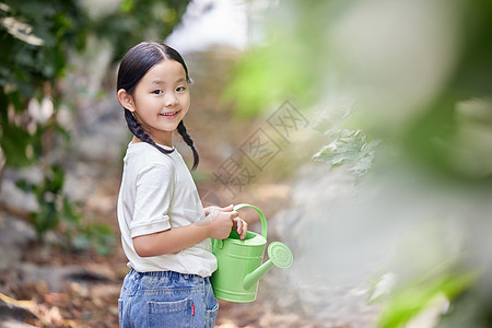 拿着洒水壶给植物浇水的小女孩背景图片