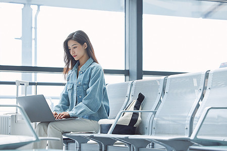 女性旅行出游在机场使用笔记本电脑图片