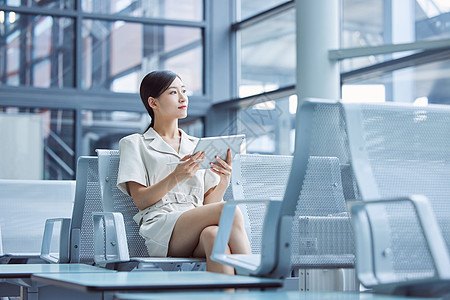 机场出差的商务女性手拿平板电脑图片