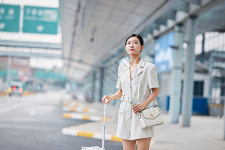 拉着行李箱焦急等车的商务女性图片