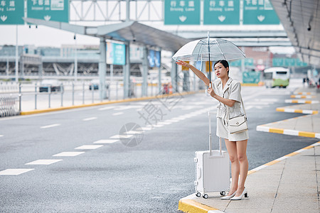 撑着伞在路边打车的商务女性背景图片