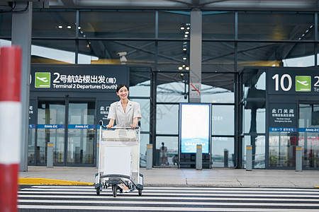 推着行李箱走在机场外的商务女性图片