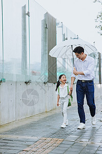 儿童雨伞年轻父亲牵手接女儿放学背景