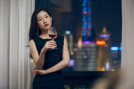 气质美女夜晚端着红酒杯站在窗前图片