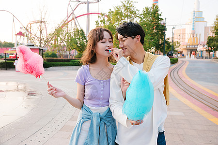 迪士尼游乐场年轻美女吃男朋友喂的棉花糖背景