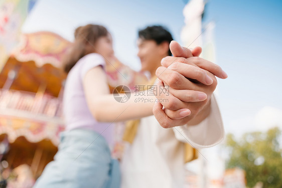 年轻情侣在游乐园牵着手特写图片
