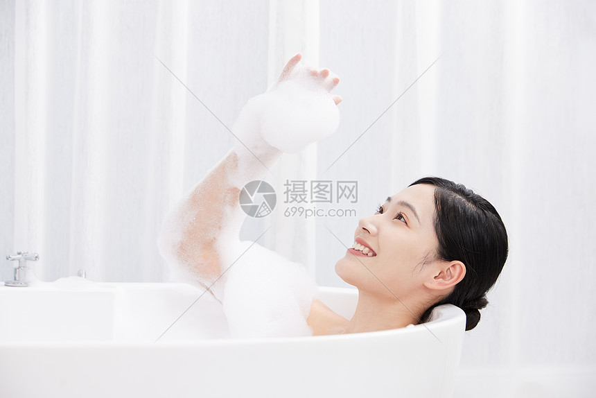 年轻女性躺在浴缸洗泡泡浴玩泡泡图片
