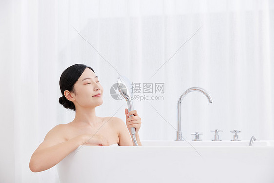 青年女性手拿花洒洗泡泡浴图片