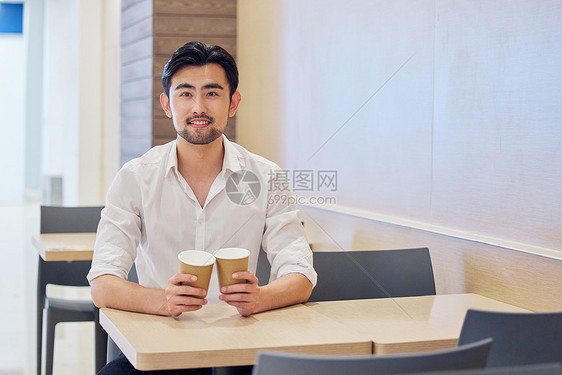 男性手拿咖啡在店里等候图片