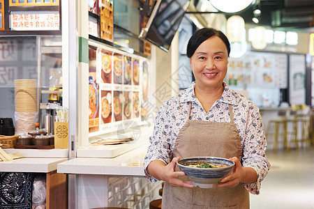 面馆logo手端大碗面条的中年女店员背景