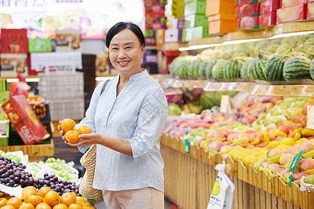 健康消费水果店内中年妇女挑选橘子背景