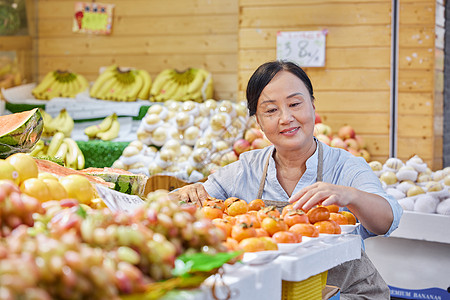 妇女检查中年水果店员工检查橘子背景