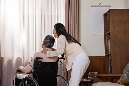 母女背影女青年关爱坐轮椅的年迈老奶奶背景