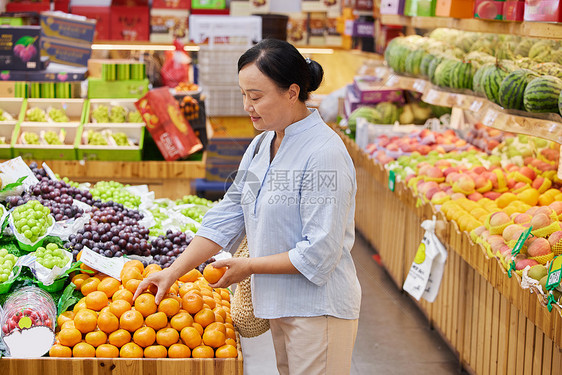 水果店内中年妇女挑选水果图片