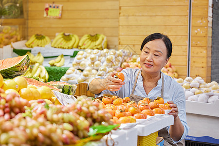 中年水果店员工检查水果品质背景图片