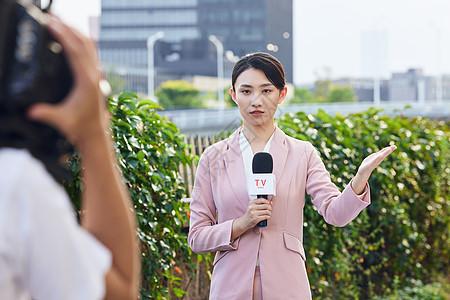 年轻女新闻记者户外采访录制背景图片