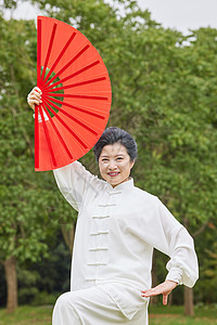 穿太极服舞扇子的老年女性背景图片