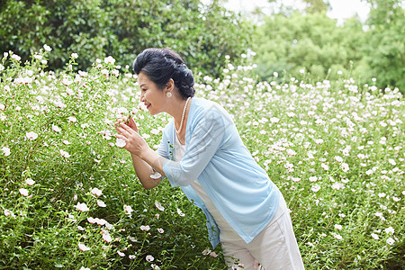 公园闻花香的中老年女性图片