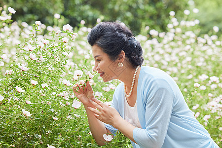 唯美女性公园闻花香的中年女性背景