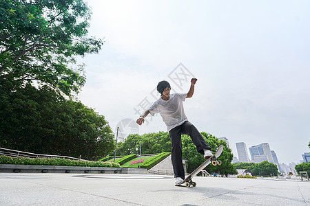 青年公园滑板少年户外玩滑板做动作背景