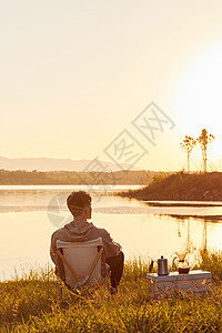 男生旅行中的背影年轻男生坐在湖边看夕阳背影背景