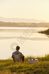 户外聚会年轻男生坐在湖边背影背景