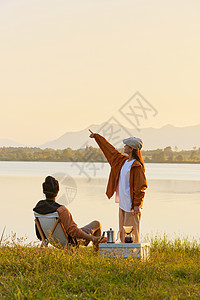 在湖边的男孩儿年轻情侣傍晚在湖边聊天背景