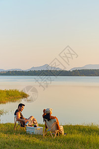 夕阳情侣年轻情侣旅行湖边享受大自然背景