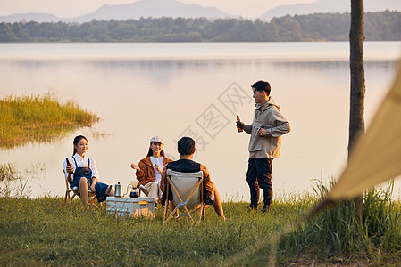 户外野餐年轻人傍晚在湖边聚会聊天背景