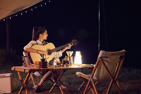 年轻美女夜晚露营弹吉他图片