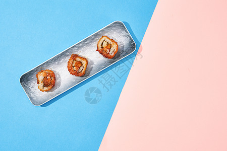 蓝粉撞色背景下的寿司卷图片