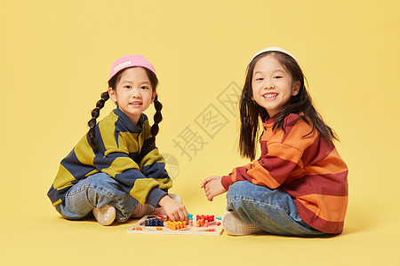 双胞胎小女孩坐地上下跳棋图片