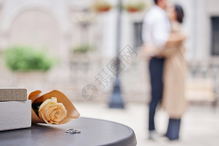 恩爱情侣相拥背景下的戒指和鲜花图片