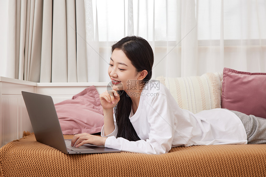 美女居家趴在沙发上用电脑网购图片