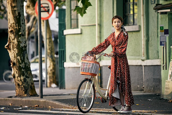 清新美女出游推着自行车过马路图片