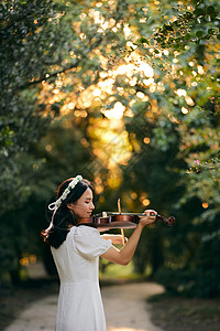 艺用美女素材夕阳余晖中拉小提琴的少女背景