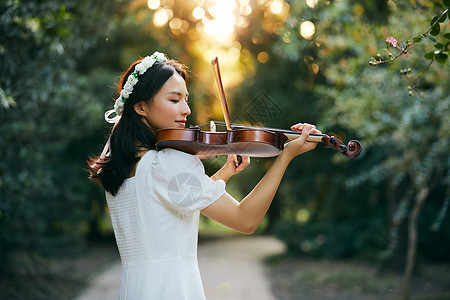 夕阳余晖中拉小提琴的少女图片