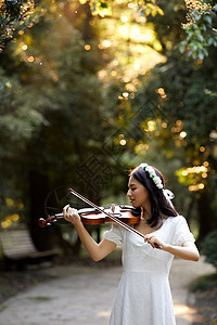 森林美女夕阳余晖中拉小提琴的少女背景
